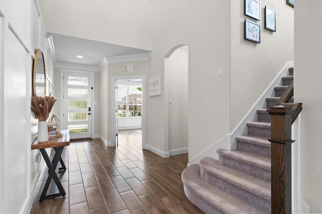 entryway with ornamental molding, baseboards, stairway, arched walkways, and dark wood finished floors