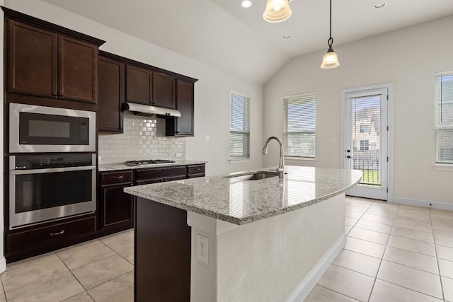 kitchen featuring light tile patterned flooring, under cabinet range hood, a sink, appliances with stainless steel finishes, and vaulted ceiling