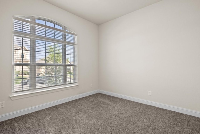 carpeted spare room featuring baseboards