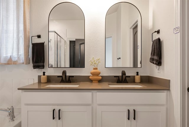 full bath with double vanity, a sink, and a shower with door