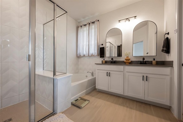 bathroom with double vanity, a stall shower, and a bath
