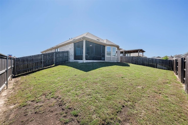 rear view of property with a lawn, a fenced backyard, and a sunroom