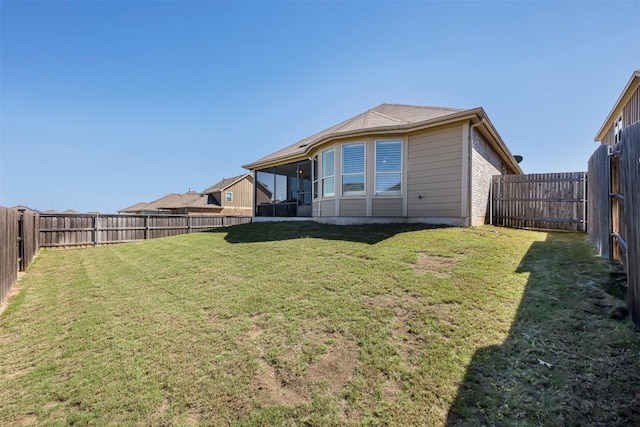 rear view of property featuring a sunroom, a fenced backyard, and a yard