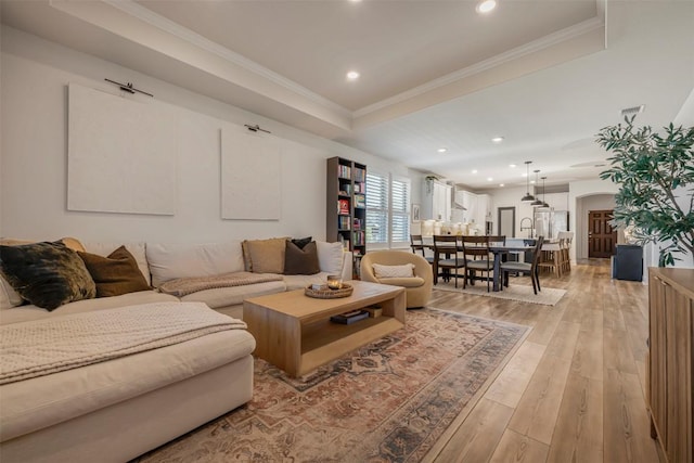 living room featuring recessed lighting, ornamental molding, light wood-style flooring, and arched walkways