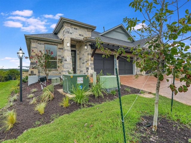 view of front of house featuring concrete driveway, a front lawn, stone siding, and a garage