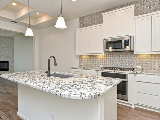 kitchen with visible vents, light stone countertops, wood finished floors, a sink, and stainless steel appliances