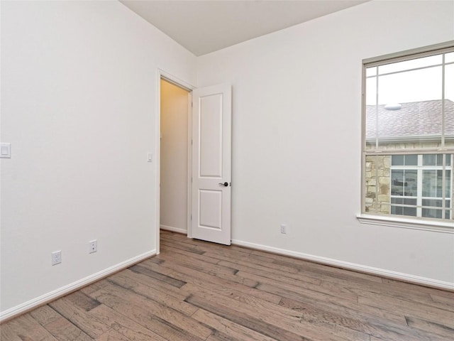 spare room with baseboards and wood finished floors