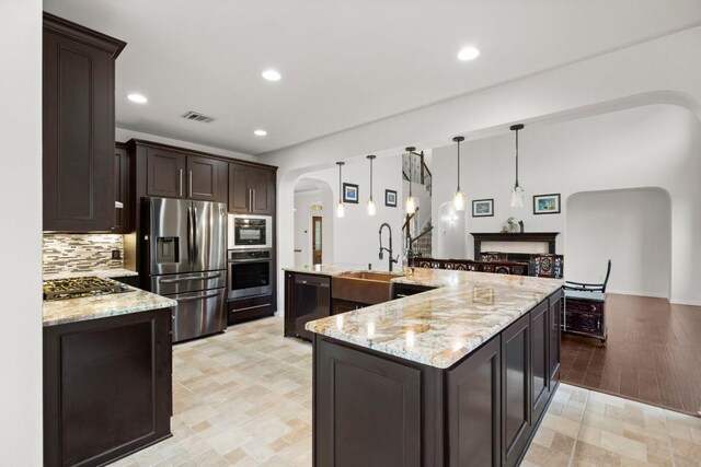 715 Nelson Ranch Rd, Cedar Park, TX 78613 - kitchen with dark brown cabinets, a sink, arched walkways, stainless steel appliances, and visible vents