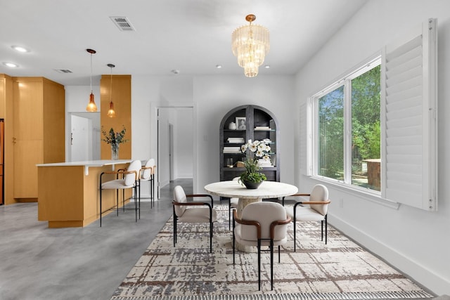 dining space with concrete flooring, a chandelier, plenty of natural light, and visible vents