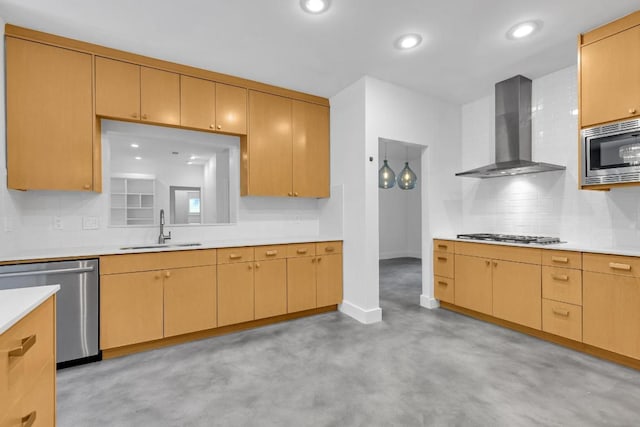 kitchen with decorative backsplash, wall chimney range hood, light countertops, a sink, and appliances with stainless steel finishes