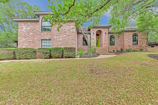 view of front facade with brick siding and a front yard
