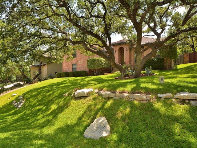 view of front of home with brick siding, fence, and a front yard