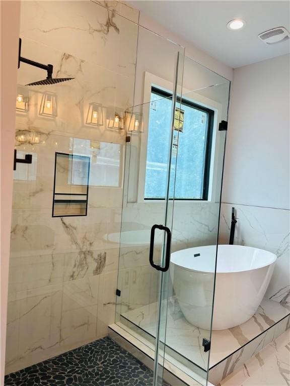 6308 Hudson Bend Rd, Austin, TX 78734 - full bathroom with marble finish floors, a soaking tub, a marble finish shower, recessed lighting, and tile walls