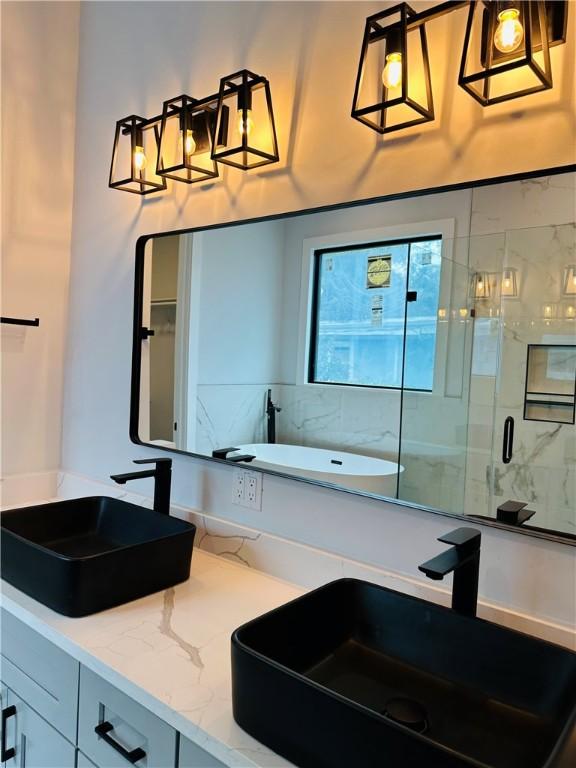 bathroom featuring vanity, a tub to relax in, and a stall shower