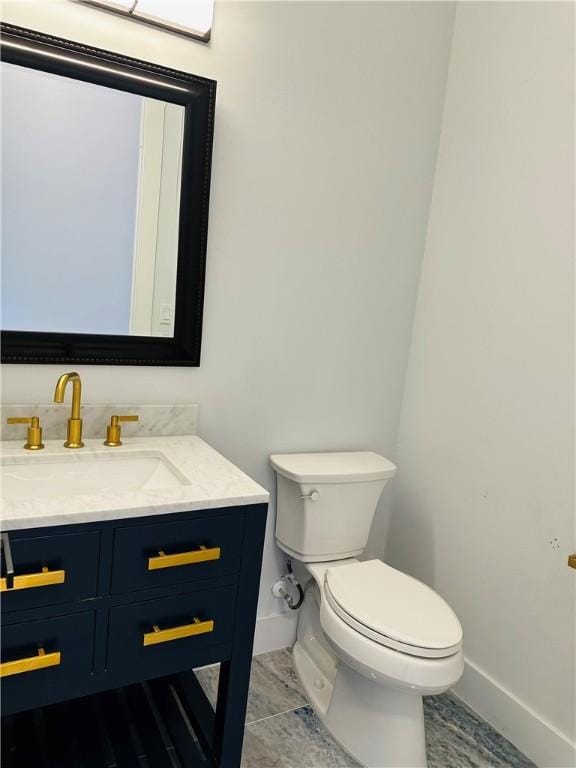 half bath with baseboards, toilet, and vanity