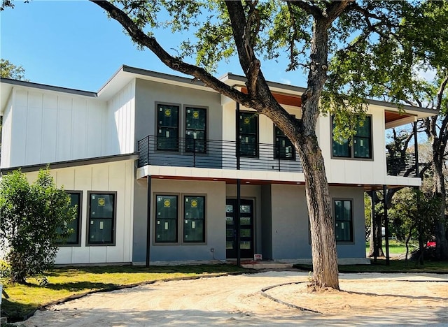 view of front of property featuring french doors, stucco siding, and a balcony
