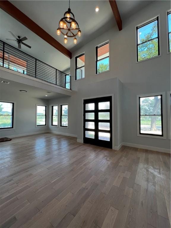 foyer with baseboards, a towering ceiling, beam ceiling, and a wealth of natural light