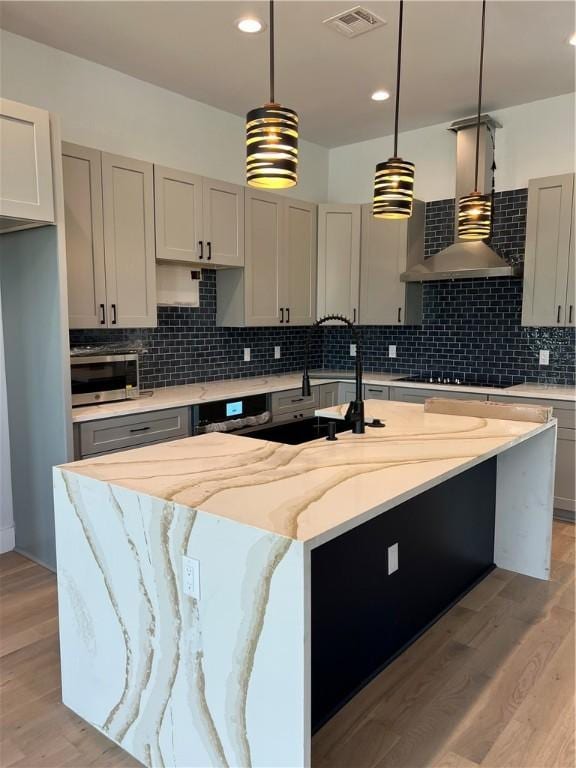 6308 Hudson Bend Rd, Austin, TX 78734 - kitchen featuring stainless steel microwave, black stovetop, decorative backsplash, light wood-type flooring, and light stone countertops