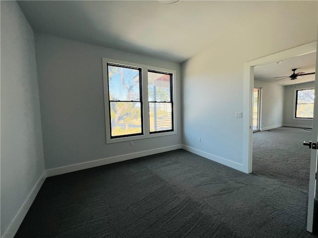 unfurnished room with baseboards and dark colored carpet