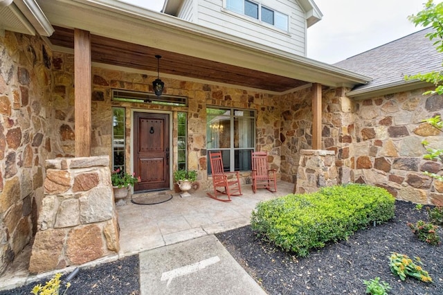 doorway to property featuring a porch and stone siding