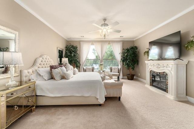 bedroom featuring ceiling fan, crown molding, baseboards, a glass covered fireplace, and light carpet