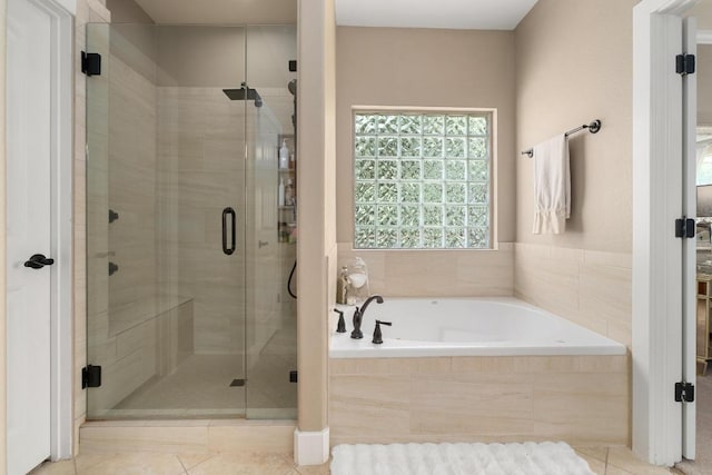 full bathroom featuring tile patterned floors, a bath, and a stall shower