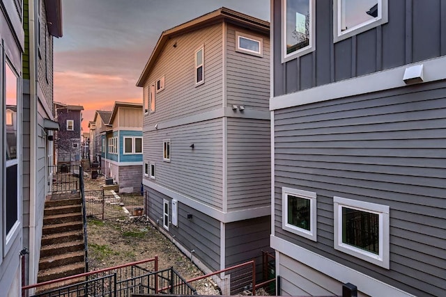 property exterior at dusk featuring board and batten siding and stairway