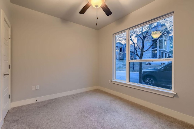 empty room featuring carpet floors, a ceiling fan, and baseboards