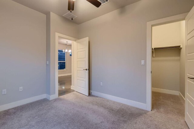 unfurnished bedroom featuring carpet floors, baseboards, visible vents, and a walk in closet