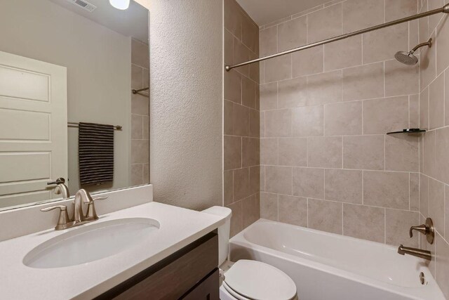 bathroom with bathing tub / shower combination, a textured wall, vanity, and toilet