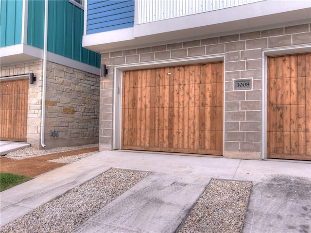 view of exterior entry featuring board and batten siding, an attached garage, and stone siding