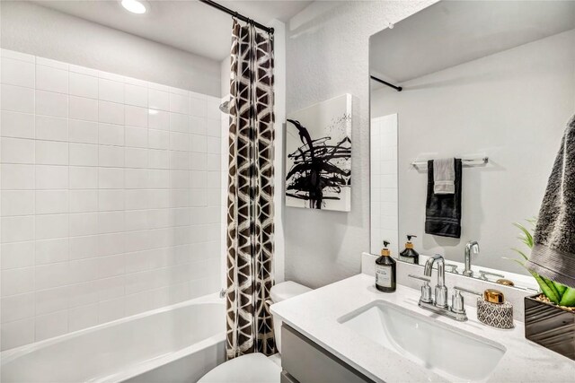 bathroom with shower / bath combo with shower curtain, a textured wall, toilet, and vanity
