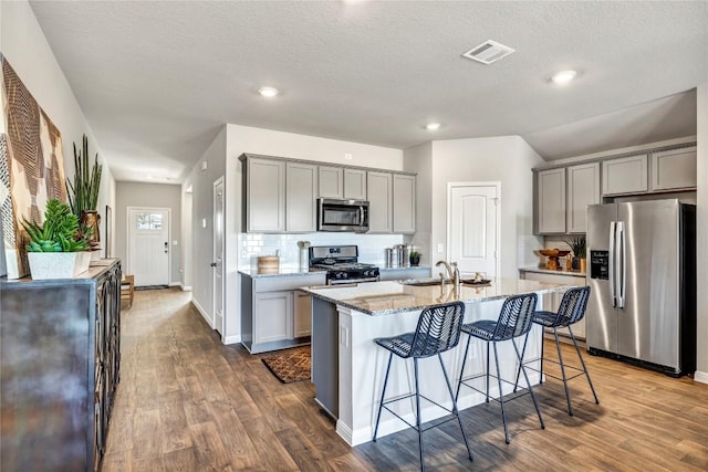 kitchen with visible vents, decorative backsplash, gray cabinetry, and stainless steel appliances