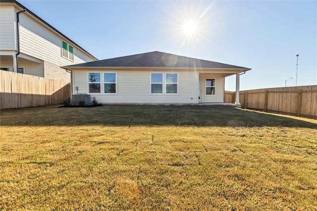 rear view of house with a lawn, a fenced backyard, and central air condition unit