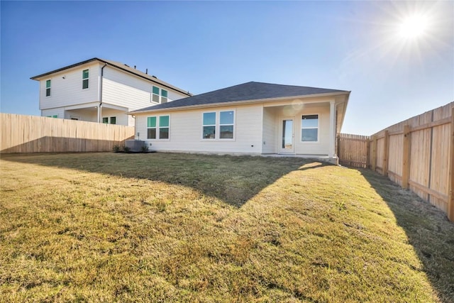 rear view of property featuring a lawn, a fenced backyard, and central air condition unit