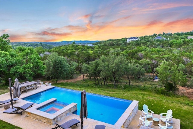 view of swimming pool featuring a patio area, a pool with connected hot tub, and outdoor dining space