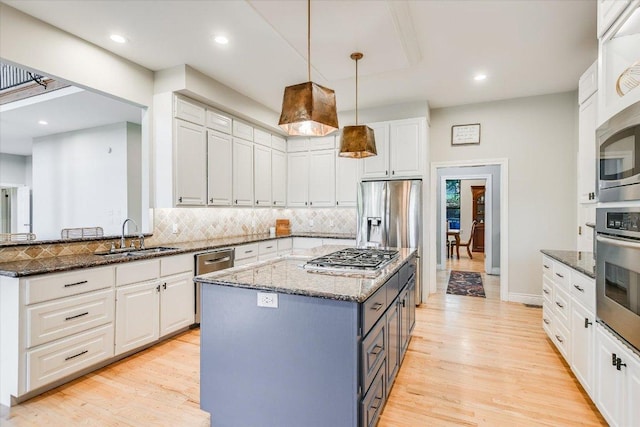 kitchen featuring decorative backsplash, light wood-type flooring, white cabinetry, a sink, and appliances with stainless steel finishes