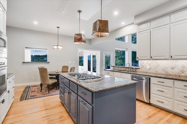 kitchen with a sink, appliances with stainless steel finishes, white cabinets, and a kitchen island