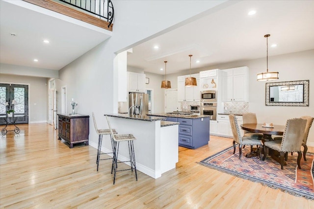 kitchen with recessed lighting, white cabinets, stainless steel appliances, and light wood-type flooring