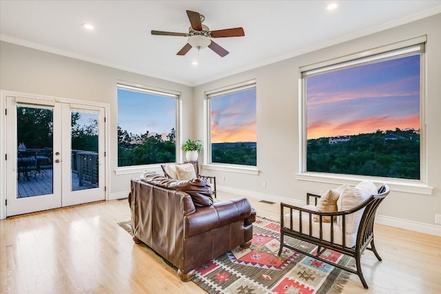 living area with crown molding, ceiling fan, french doors, baseboards, and light wood-type flooring