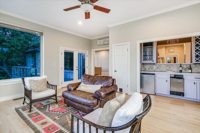 277 S Commons Ford Rd, Austin, TX 78733 - living area featuring bar with sink, light wood-style floors, ornamental molding, a ceiling fan, and baseboards