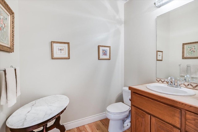 bathroom with vanity, baseboards, wood finished floors, and toilet