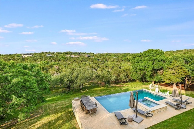 view of pool featuring a patio area, a pool with connected hot tub, and a forest view