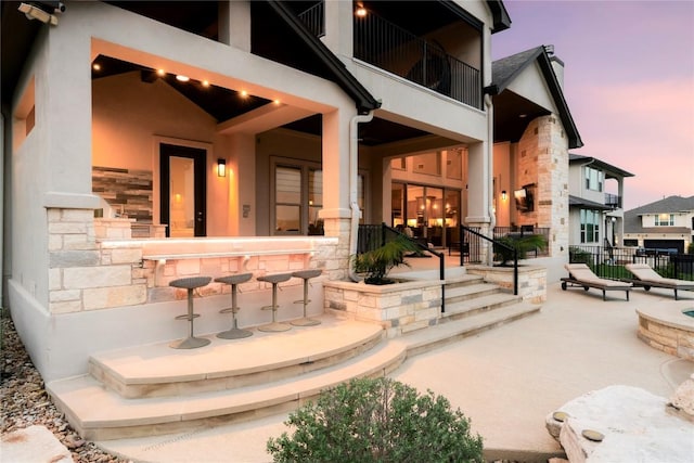 2033 Portobello Rd, Leander, TX 78641 - back of house with stone siding, a patio area, stucco siding, and a balcony