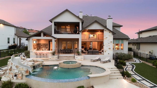 2033 Portobello Rd, Leander, TX 78641 - back of house featuring a balcony, an in-ground hot tub, a patio, a chimney, and stucco siding