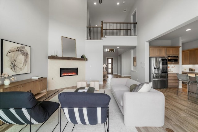 2033 Portobello Rd, Leander, TX 78641 - living area featuring a high ceiling, a glass covered fireplace, light wood-type flooring, radiator, and recessed lighting
