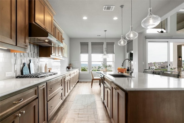 2033 Portobello Rd, Leander, TX 78641 - kitchen with a sink, under cabinet range hood, recessed lighting, light countertops, and stainless steel gas stovetop