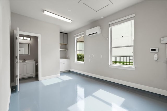 2033 Portobello Rd, Leander, TX 78641 - unfurnished room featuring a wall mounted air conditioner, finished concrete floors, baseboards, and a sink