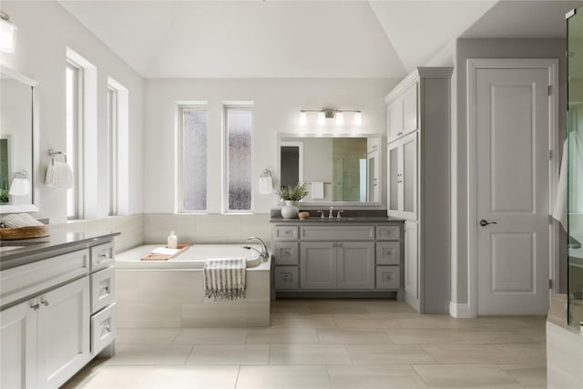 2033 Portobello Rd, Leander, TX 78641 - bathroom featuring vaulted ceiling, vanity, a garden tub, an enclosed shower, and tile patterned floors