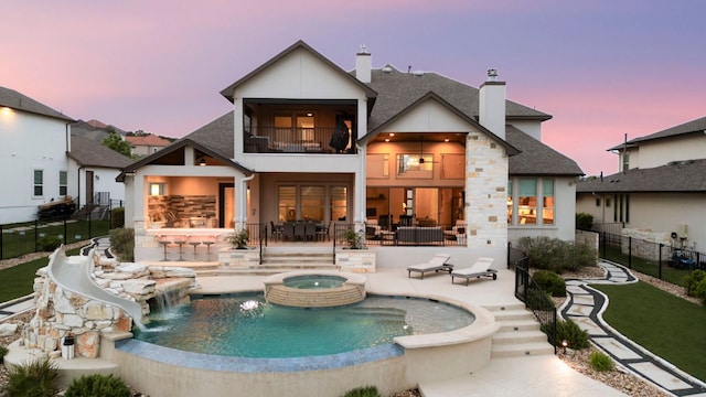 2033 Portobello Rd, Leander, TX 78641 - rear view of house with a balcony, a chimney, a patio, roof with shingles, and stone siding